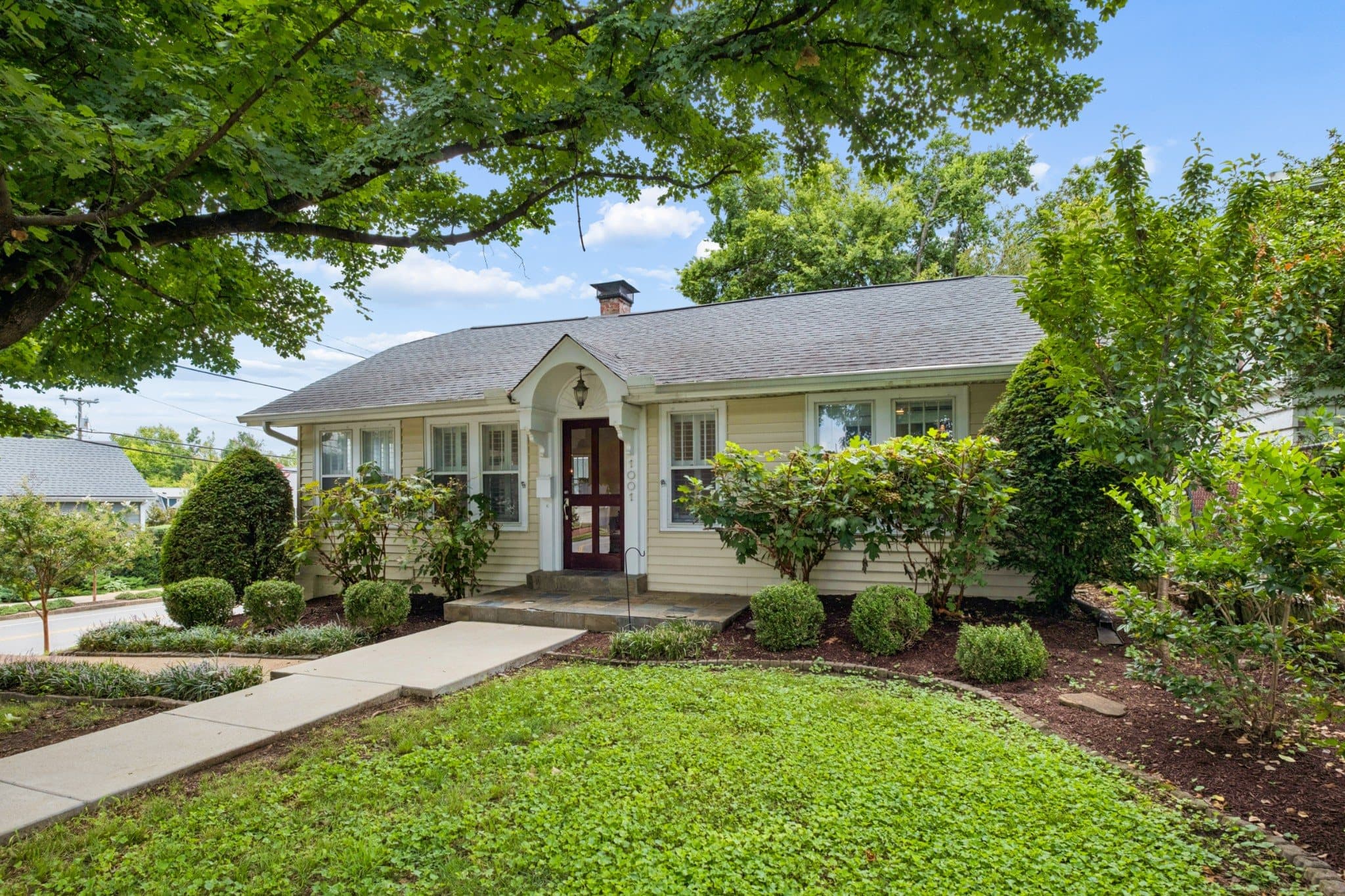 Front exterior of 1001 Caldwell Ave, a 1930 one level cottage on a corner lot with a landscaped front yard, one of the 12 South homes for sale in Nashville