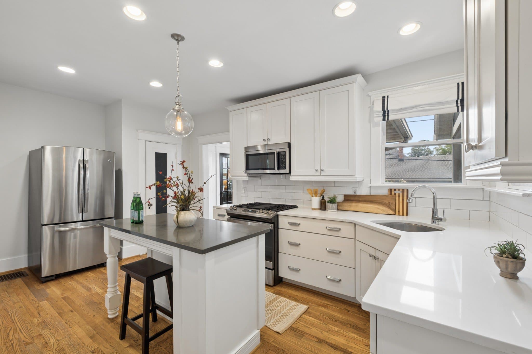 Updated kitchen with white cabinetry, a dark island with seating, and stainless appliances at 1001 Caldwell Ave in 12 South Nashville