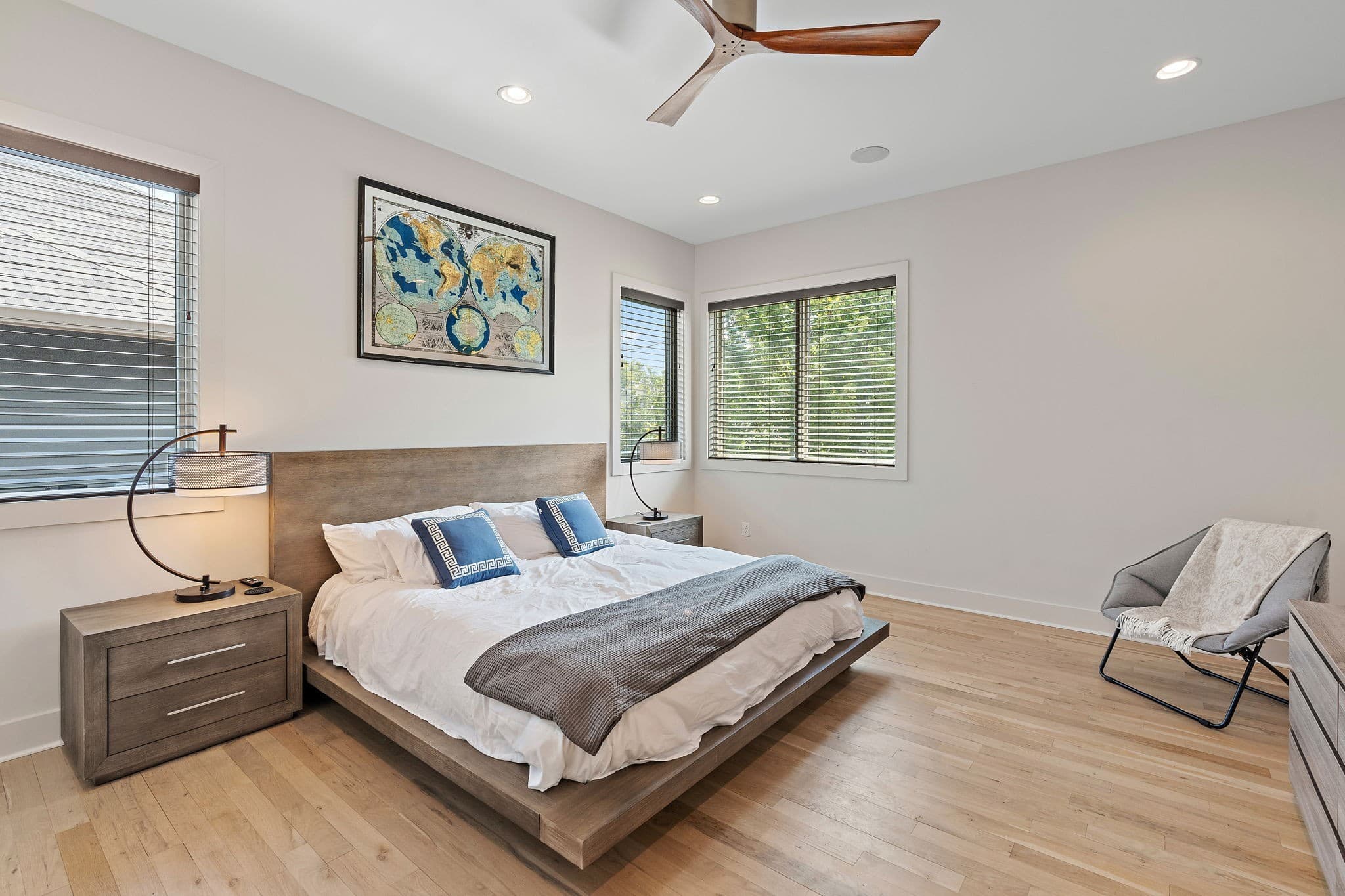 Primary bedroom with light wood floors, a ceiling fan, a low wood bed frame and windows on two walls at 1002 W Grove Avenue in 12 South Nashville