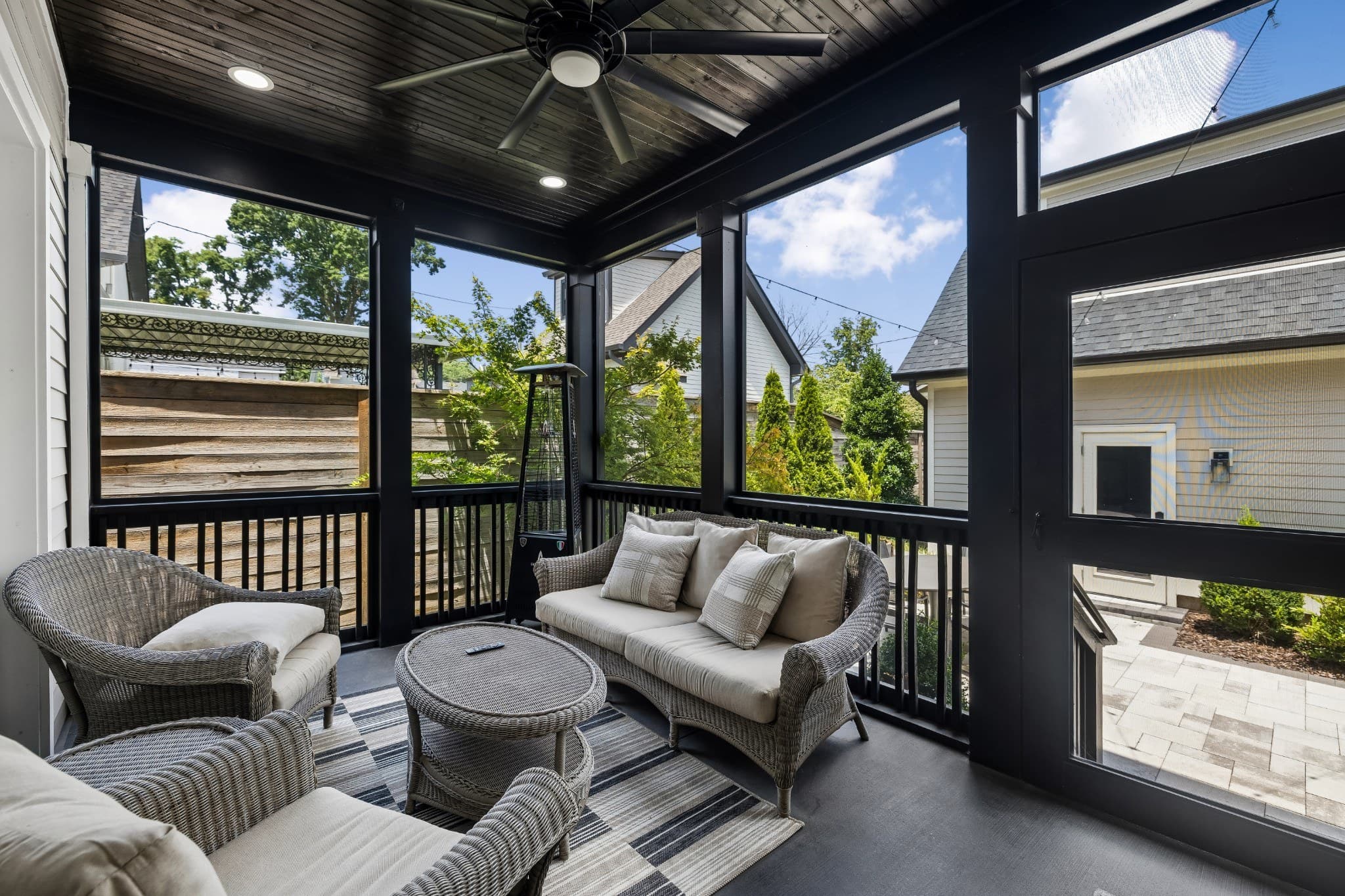Screened porch with a stained wood ceiling, a ceiling fan, wicker lounge seating and a patio heater, looking out over the courtyard at 1012 Lawrence Avenue in 12 South Nashville