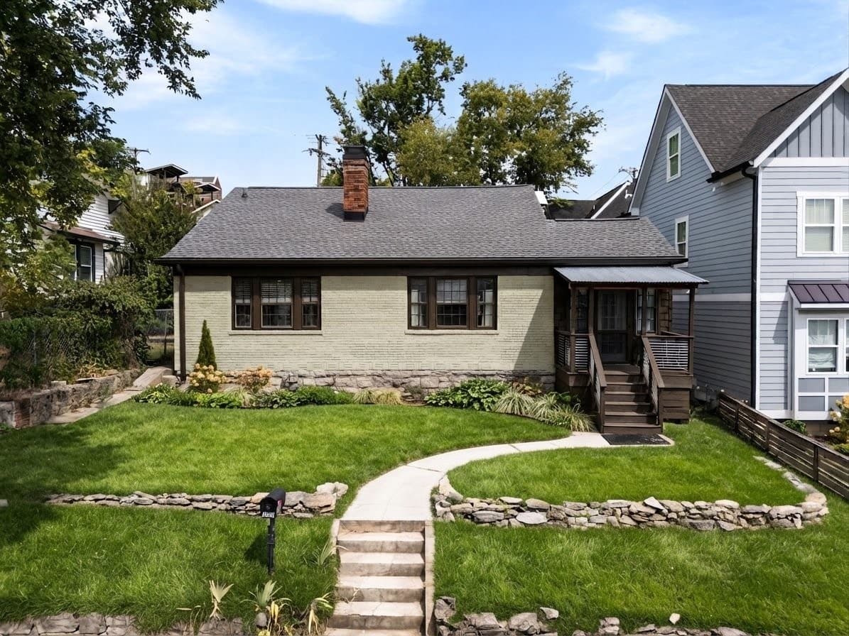 Front exterior of 1202 Ashwood Ave, a 1930 brick bungalow up on a terraced front lawn, one of the 12 South homes for sale in Nashville