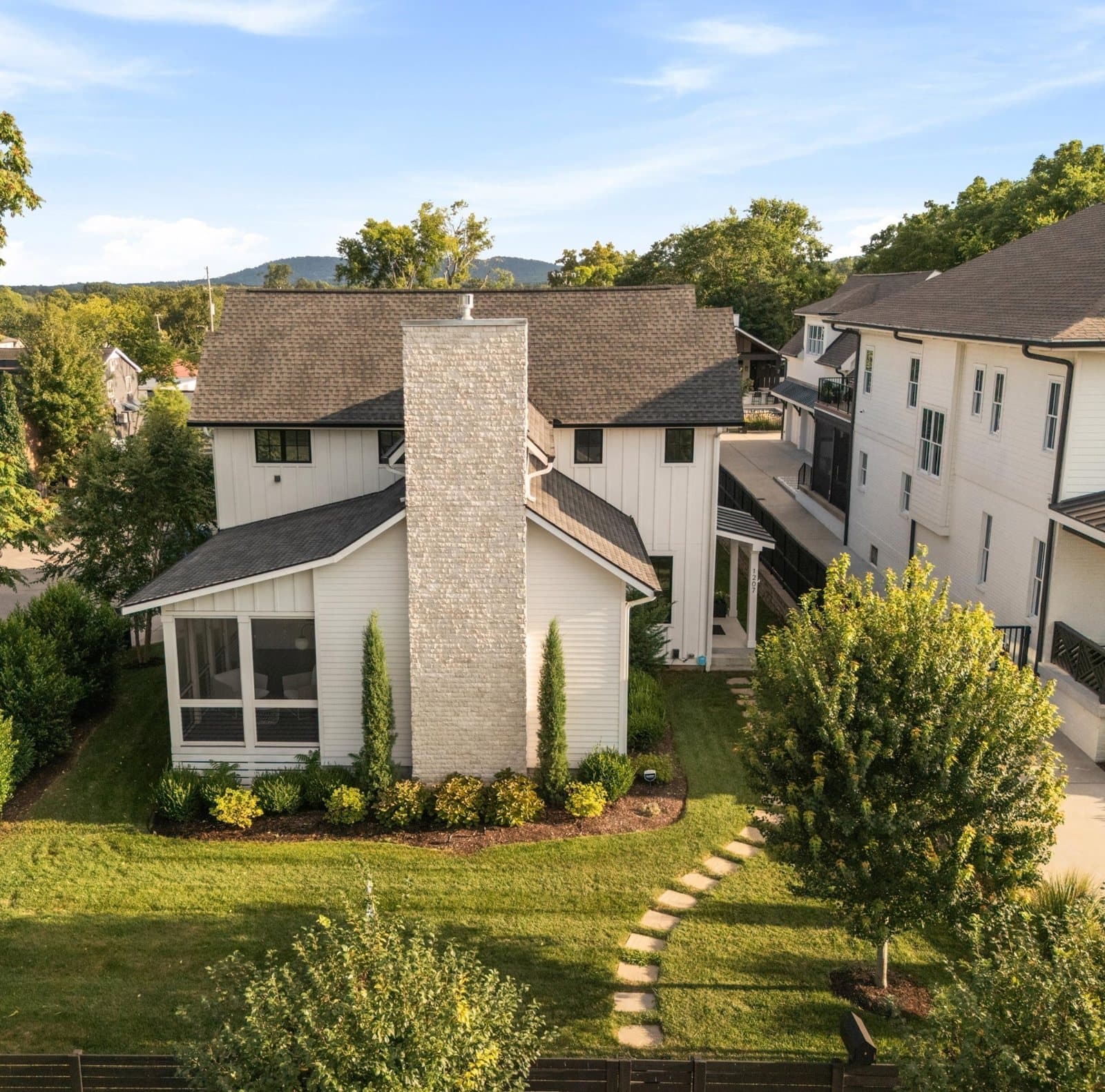 Chimney side of 1207 Sweetbriar Ave with the screened porch, landscaping and a stepping stone path in 12 South Nashville