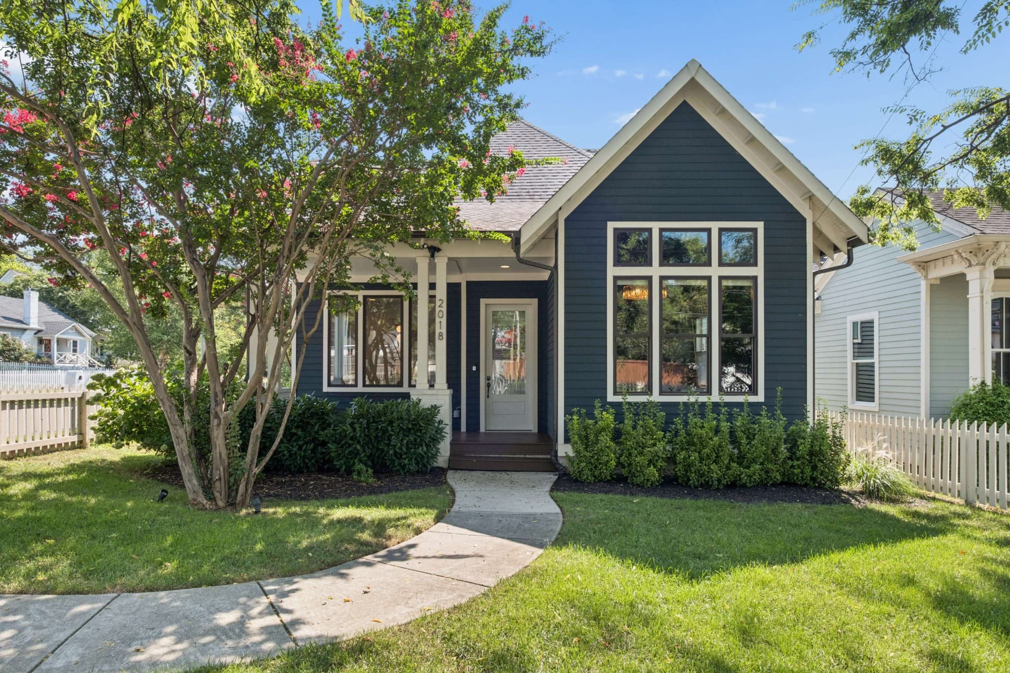 Front exterior of 2018 10th Avenue South, a dark blue 2020 home with white trim, a tall front gable full of windows, a covered front porch with white columns and a curved front walk, one of the 12 South homes for sale in Nashville