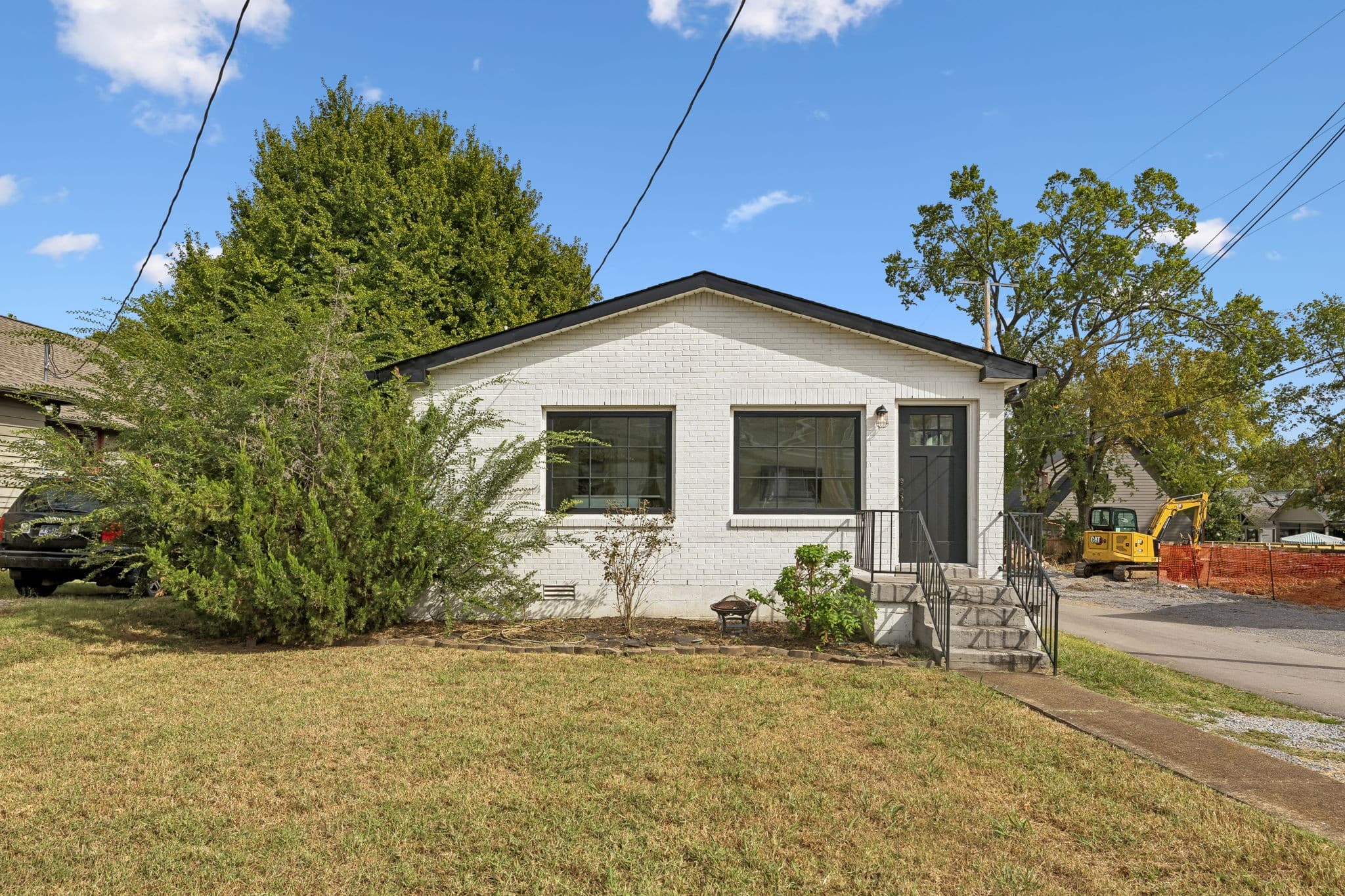 Front exterior of 2028 10th Ave S, a white painted brick ranch with black trimmed windows, one of the 12 South homes for sale in Nashville