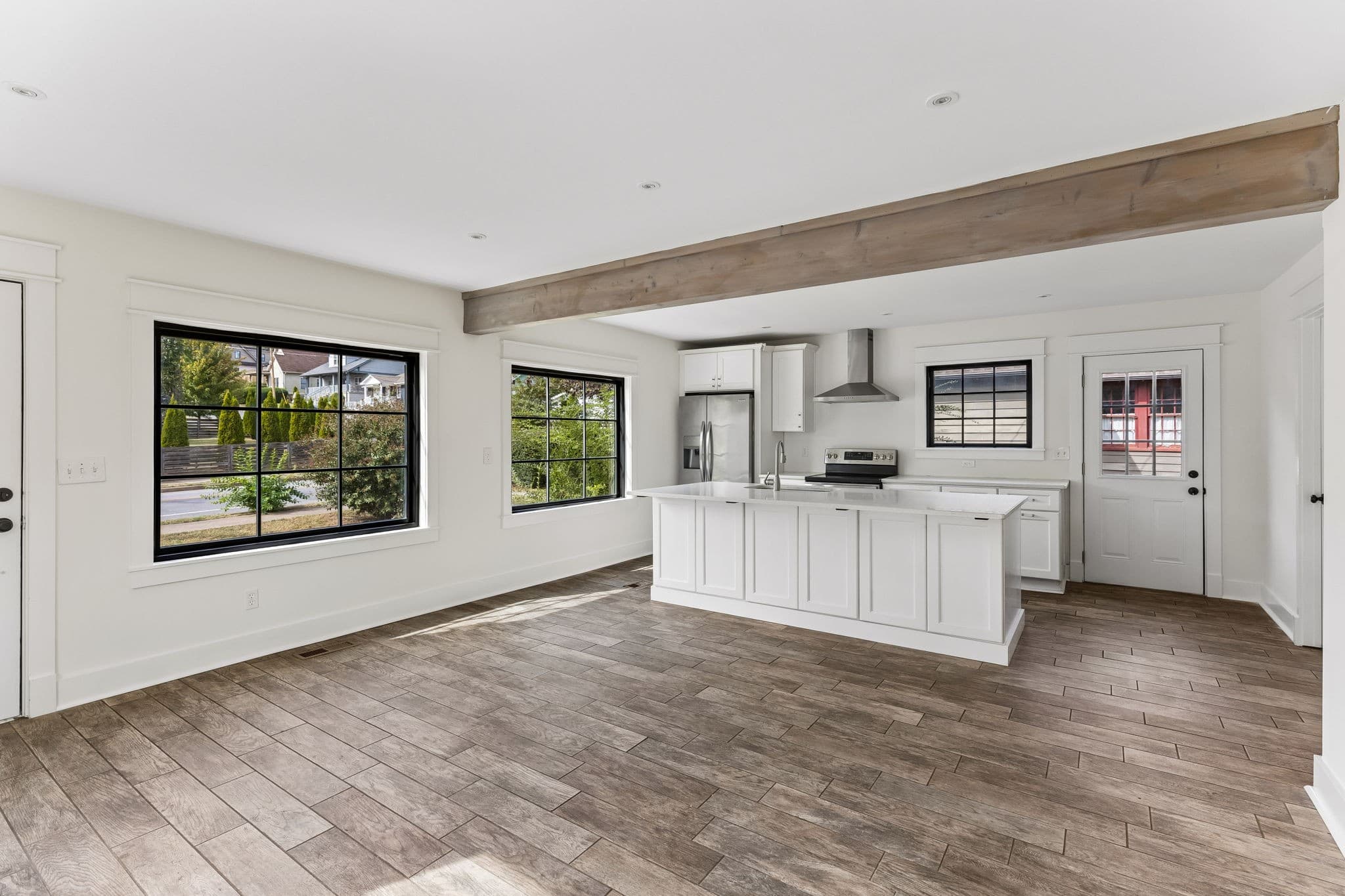 Open living room and kitchen with wood floors and an exposed wood beam at 2028 10th Ave S in 12 South Nashville