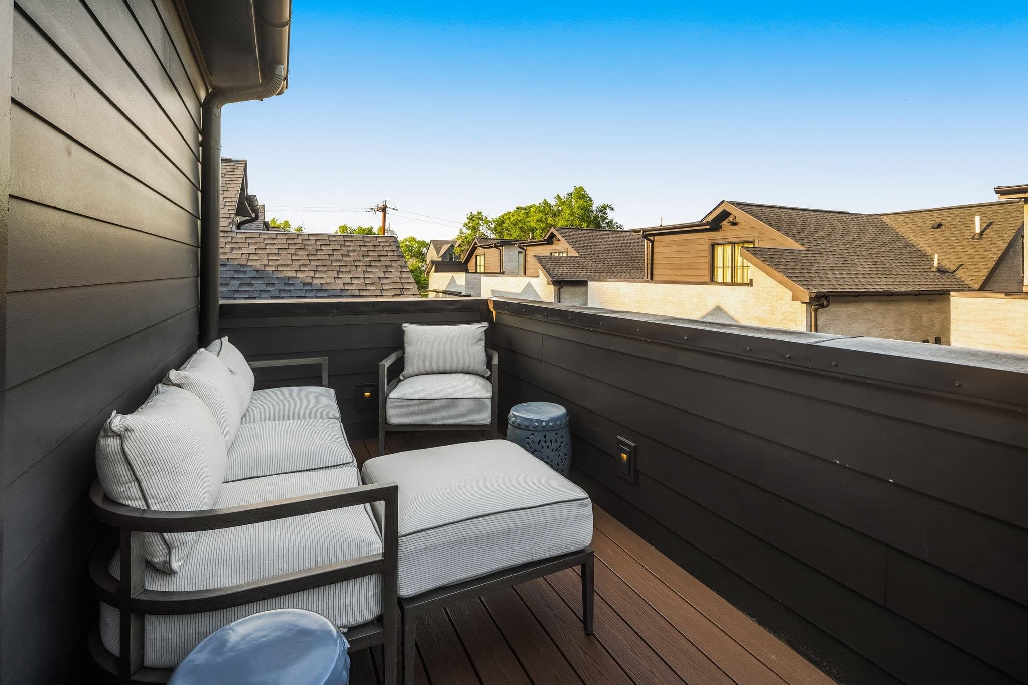 Private balcony with a dark wood deck, outdoor sofa and lounge chairs, looking out over neighboring roofs at 2086 12th Avenue South in 12 South Nashville