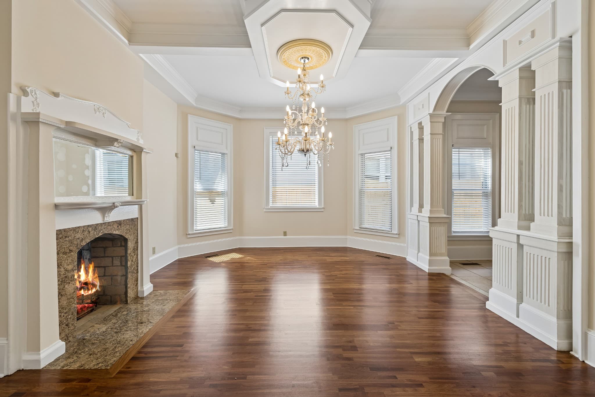 Living room with a crystal chandelier, a ceiling medallion, a fireplace with a carved mantel, bay windows and hardwood floors at 2107 10th Avenue South in 12 South Nashville