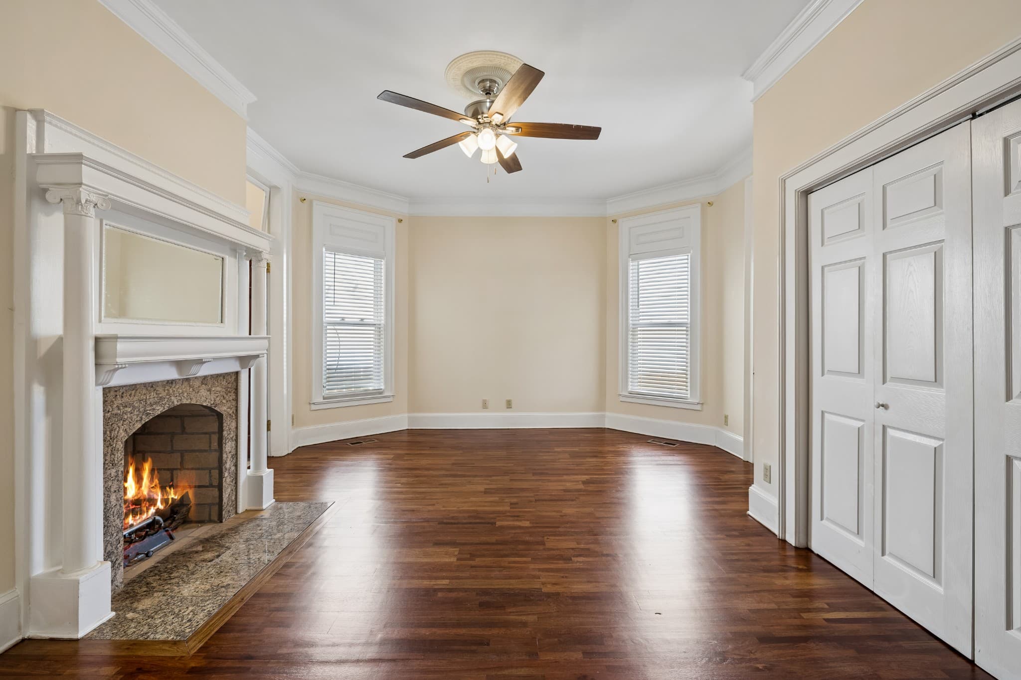 Primary bedroom with a fireplace, a white mantel, a ceiling fan, bay windows and hardwood floors at 2107 10th Avenue South in 12 South Nashville