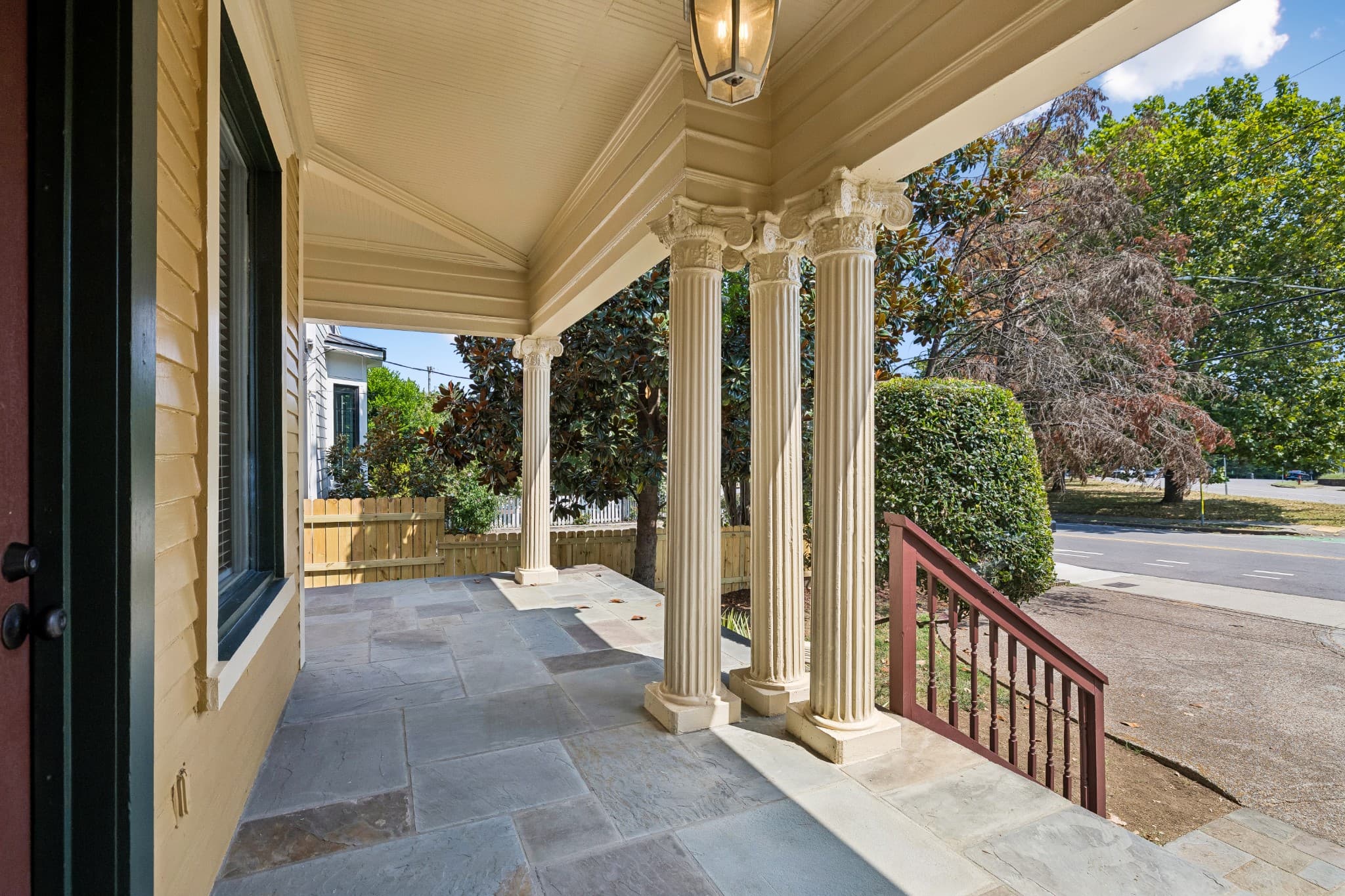 Covered front porch with a stone floor, fluted columns, a hanging lantern and a view of the street at 2107 10th Avenue South in 12 South Nashville