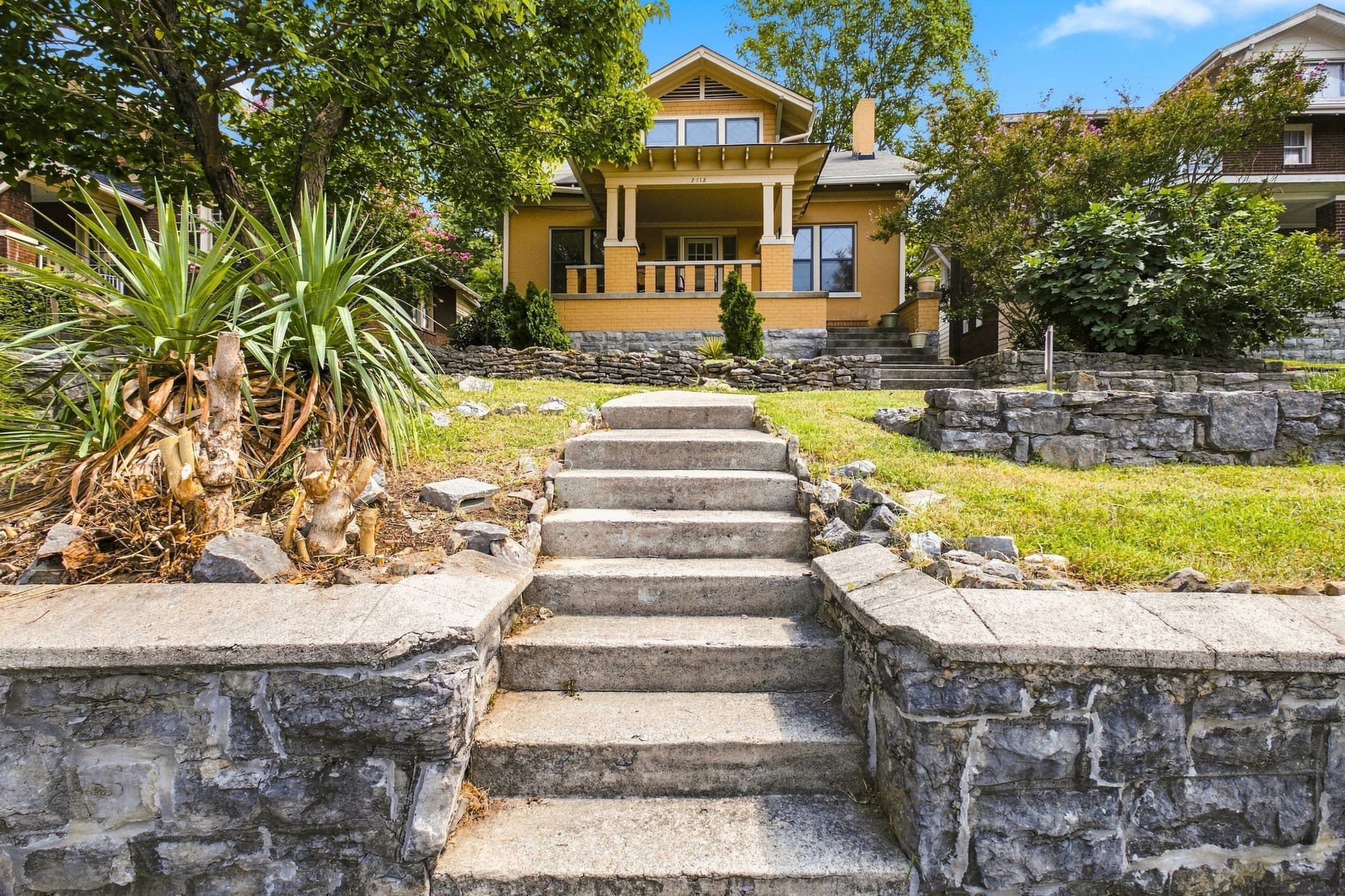 Front exterior of 2112 15th Ave S, a 1930 Colonial with a large front porch and stone steps up from the street, one of the 12 South homes for sale in Nashville