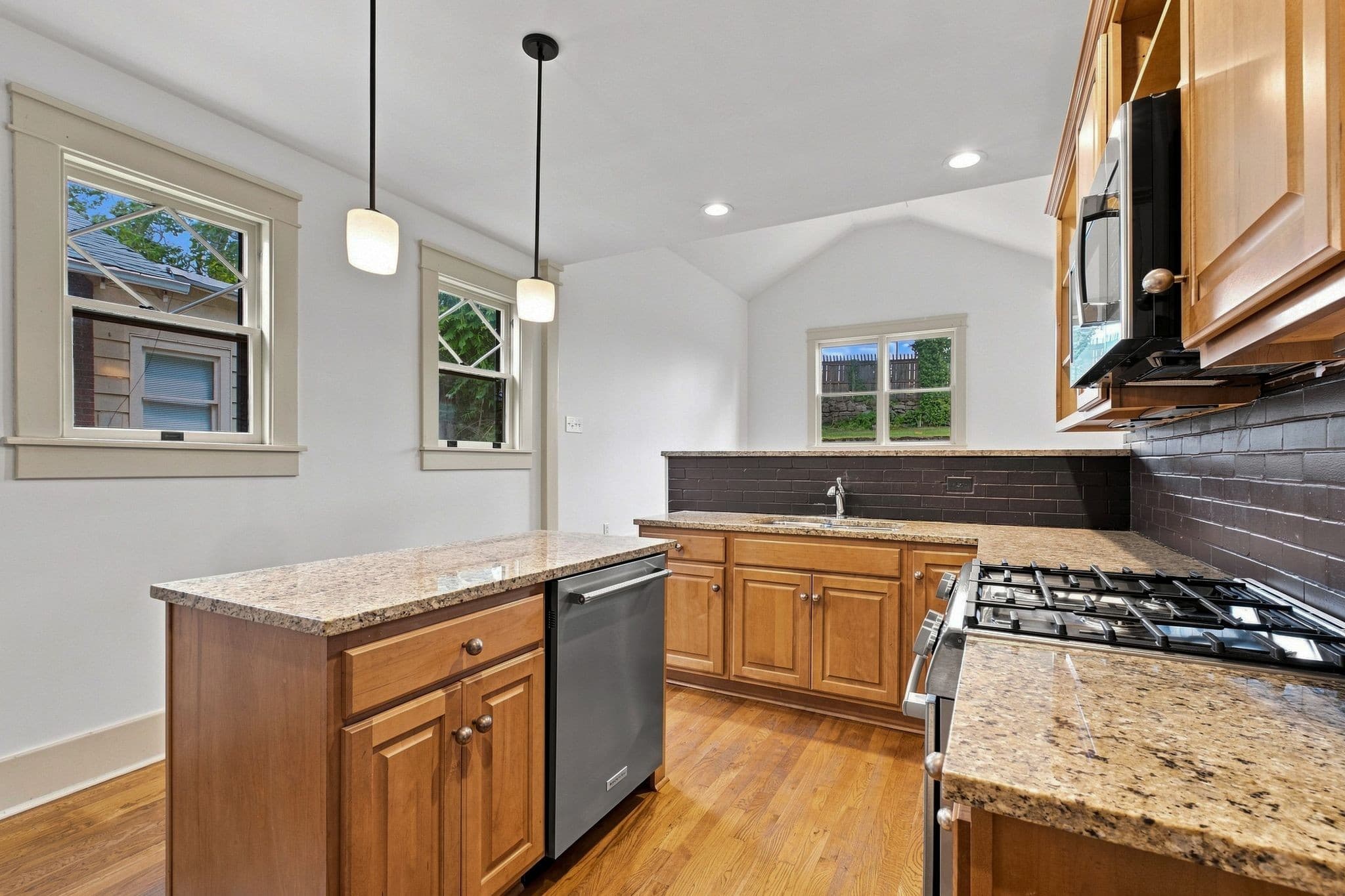 Kitchen with a granite island, pendant lights, wood cabinetry, and a gas range at 2112 15th Ave S in 12 South Nashville