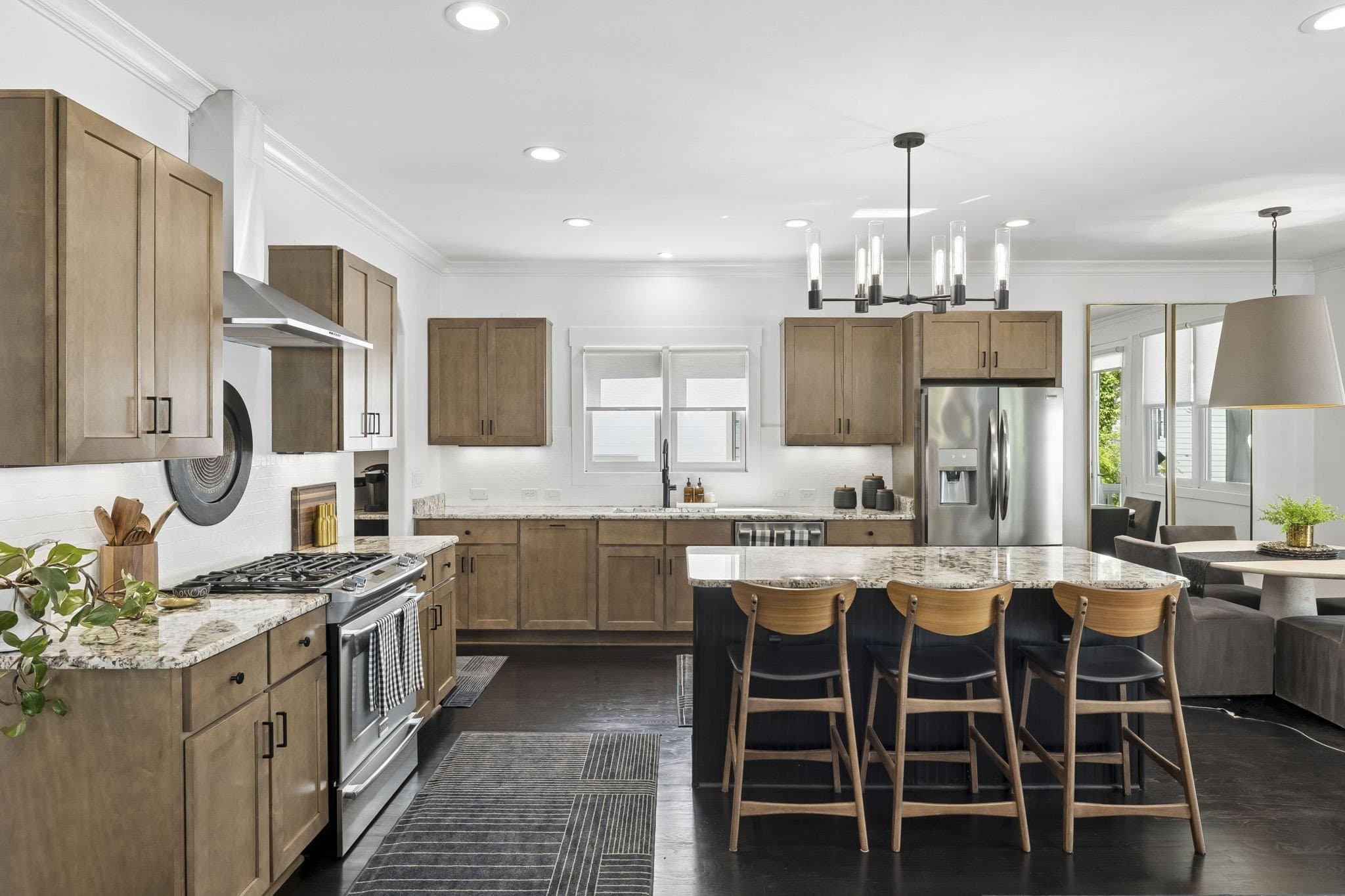 Kitchen with light wood cabinets, a dark island with three stools, a stainless gas range, a stainless refrigerator and a black chandelier at 2409 Vaulx Lane in 12 South Nashville