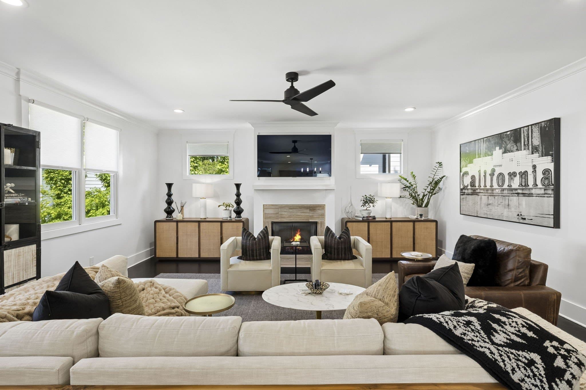 Living room with a gas fireplace, a TV above the mantel, dark hardwood floors and seating facing the fireplace at 2409 Vaulx Lane in 12 South Nashville