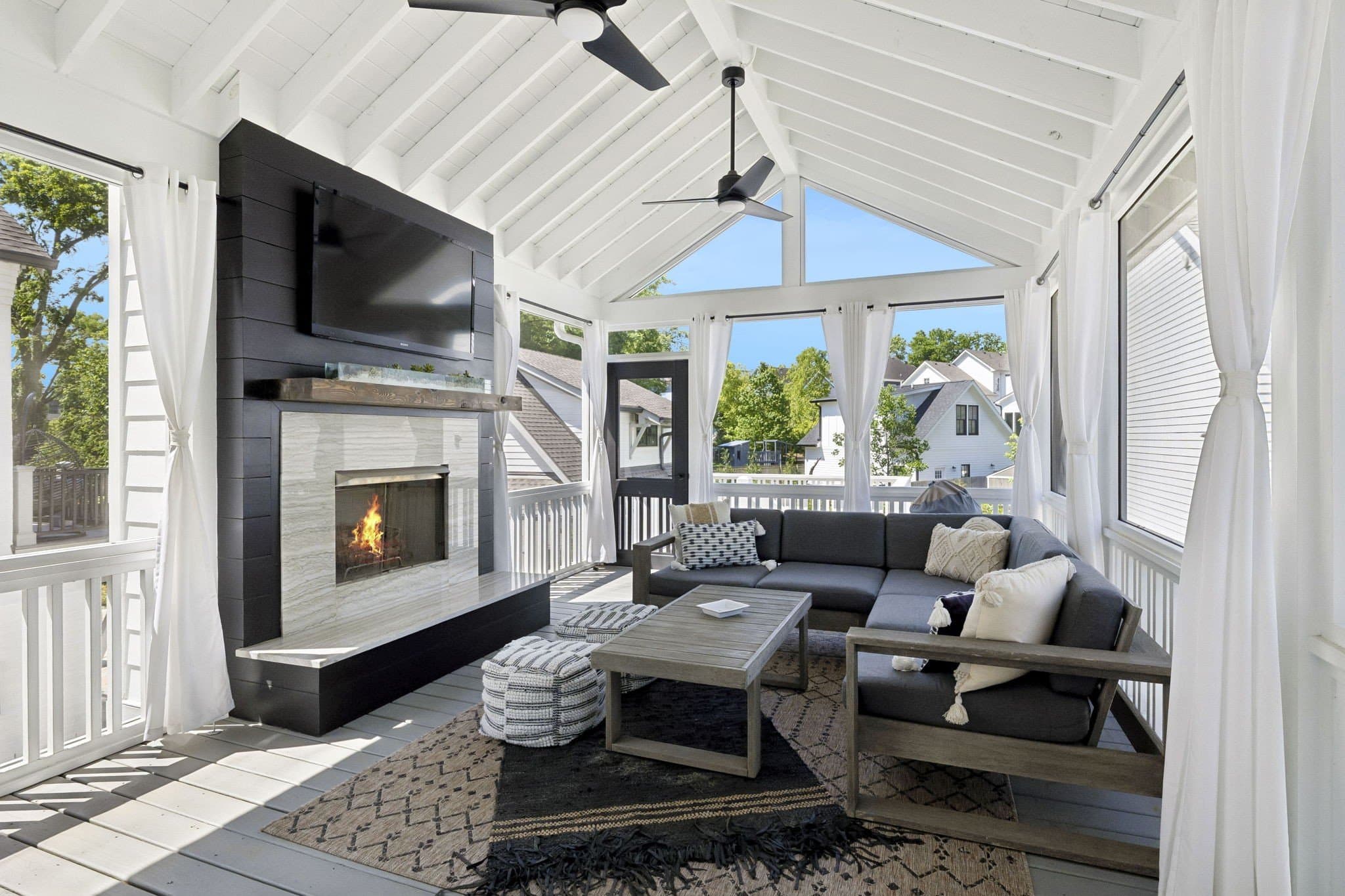 Screened Trex deck with a vaulted ceiling, a fireplace with a TV above the mantel, a sectional sofa and views of neighboring homes at 2409 Vaulx Lane in 12 South Nashville