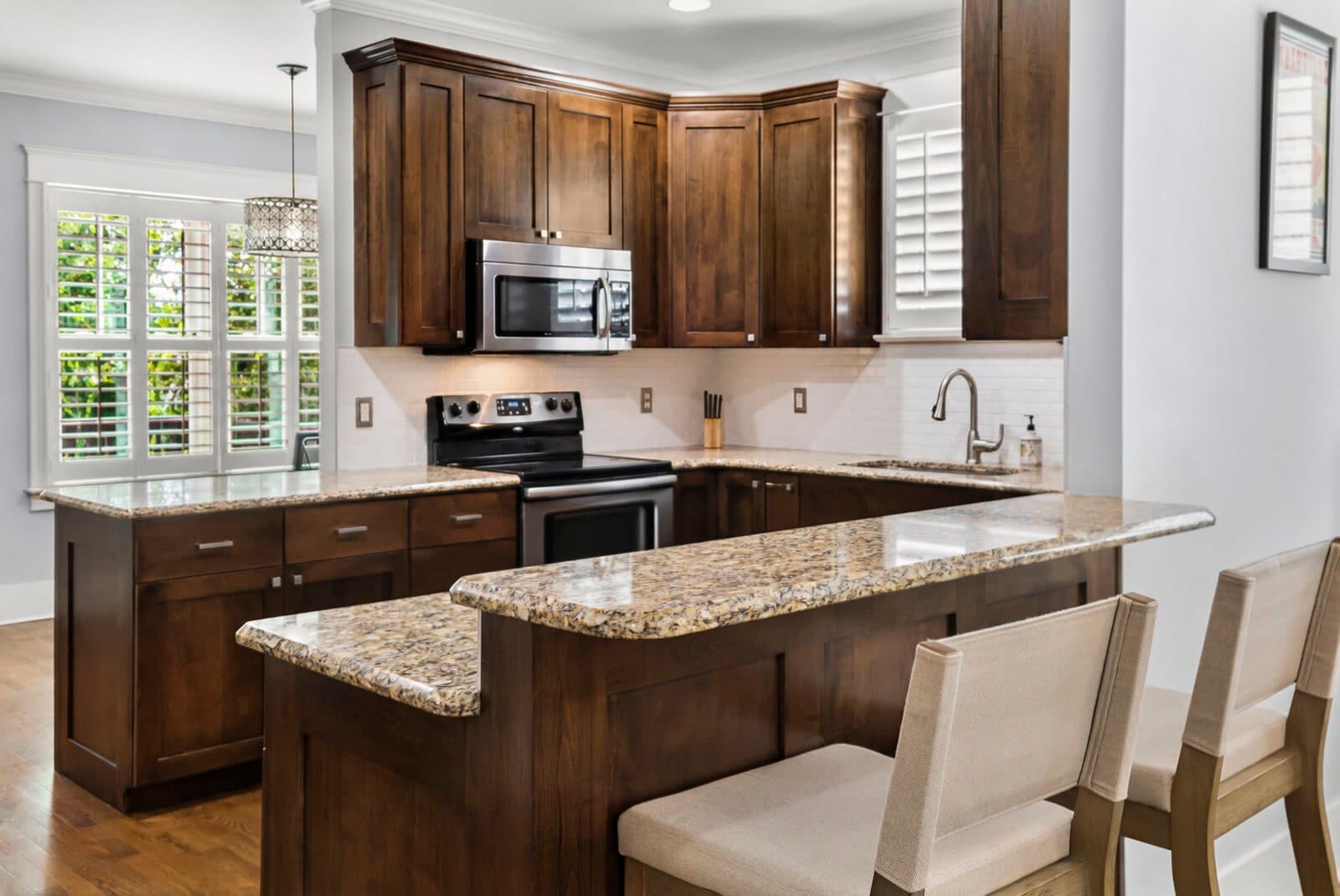 Kitchen with dark wood cabinets, granite peninsula with seating and stainless appliances at 2500B 9th Ave S in 12 South Nashville