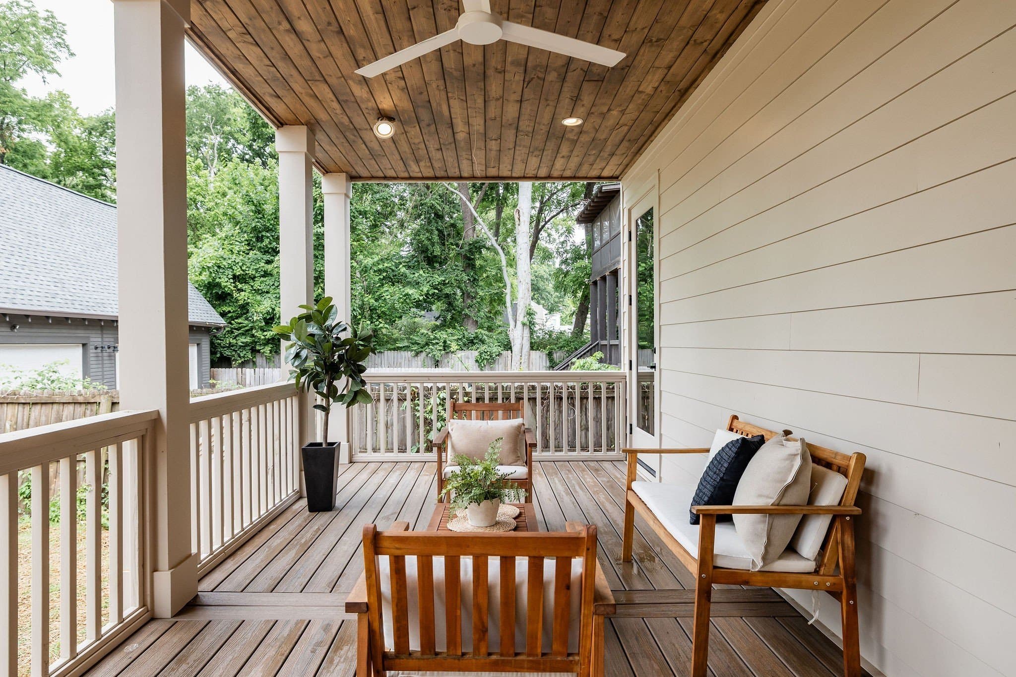 Covered screen ready porch with wood flooring, a white railing, a ceiling fan, and seating looking out to trees at 2507A Vaulx Lane in 12 South Nashville