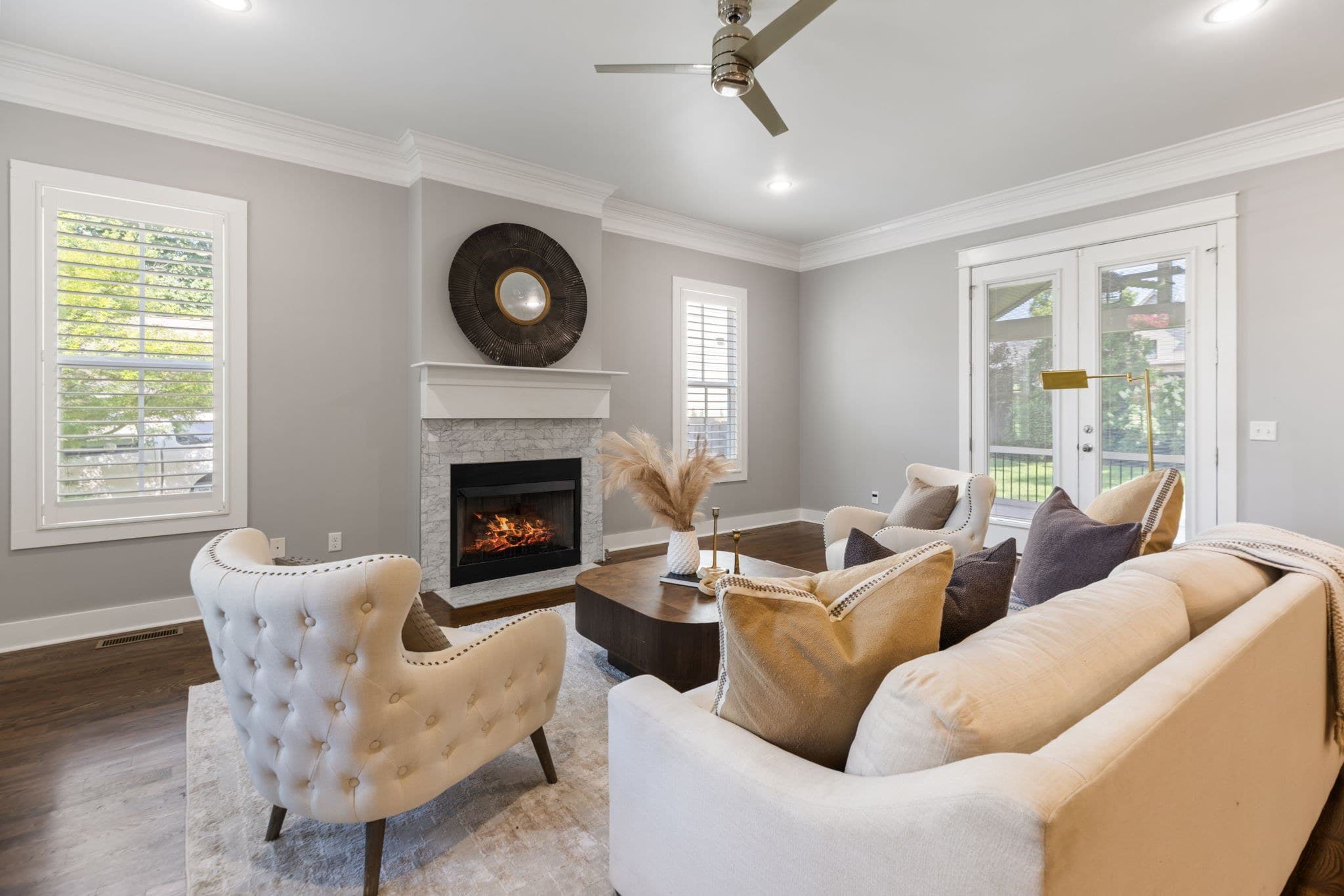 Living room with a gas fireplace and white mantel, dark hardwood floors, a ceiling fan and French doors to the porch at 908B Gale Lane in 12 South Nashville