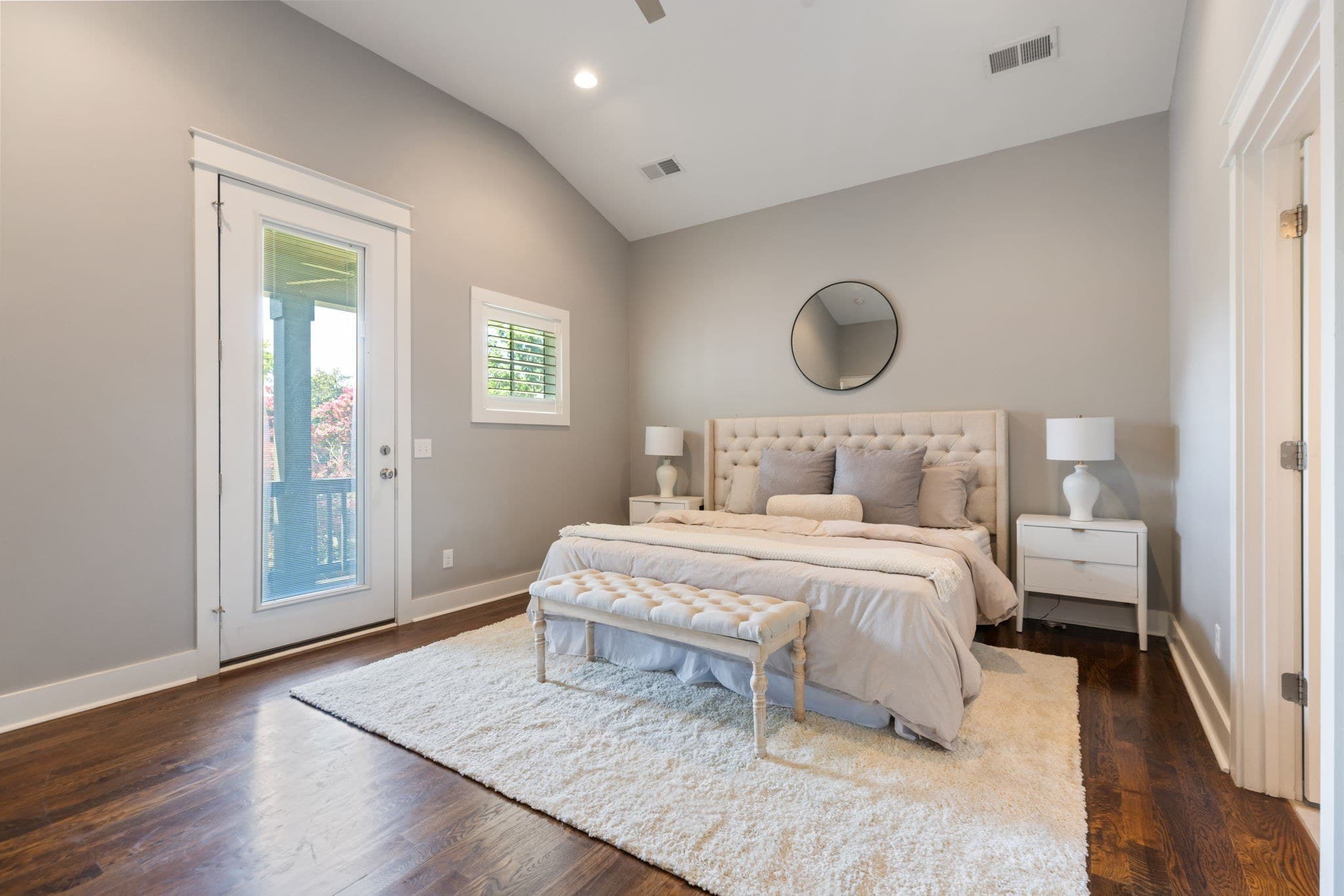 Upstairs primary bedroom with a vaulted ceiling, dark hardwood floors, an upholstered bed and a glass door to the covered balcony at 908B Gale Lane in 12 South Nashville