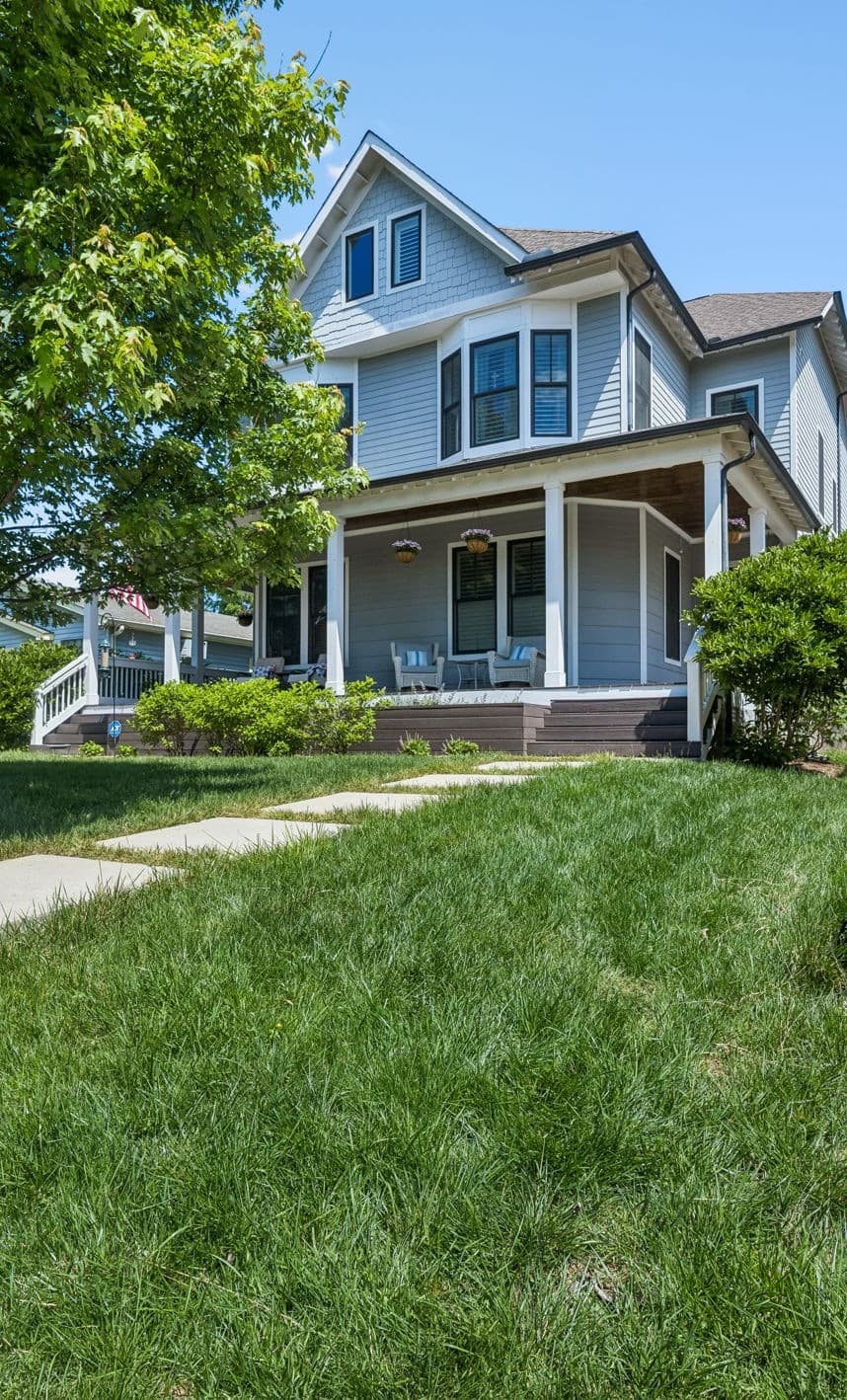 Front exterior of 916 Montrose Avenue #A, a two story gray home with a covered front porch, bay windows and a stone path across the front lawn, one of the 12 South homes for sale in Nashville