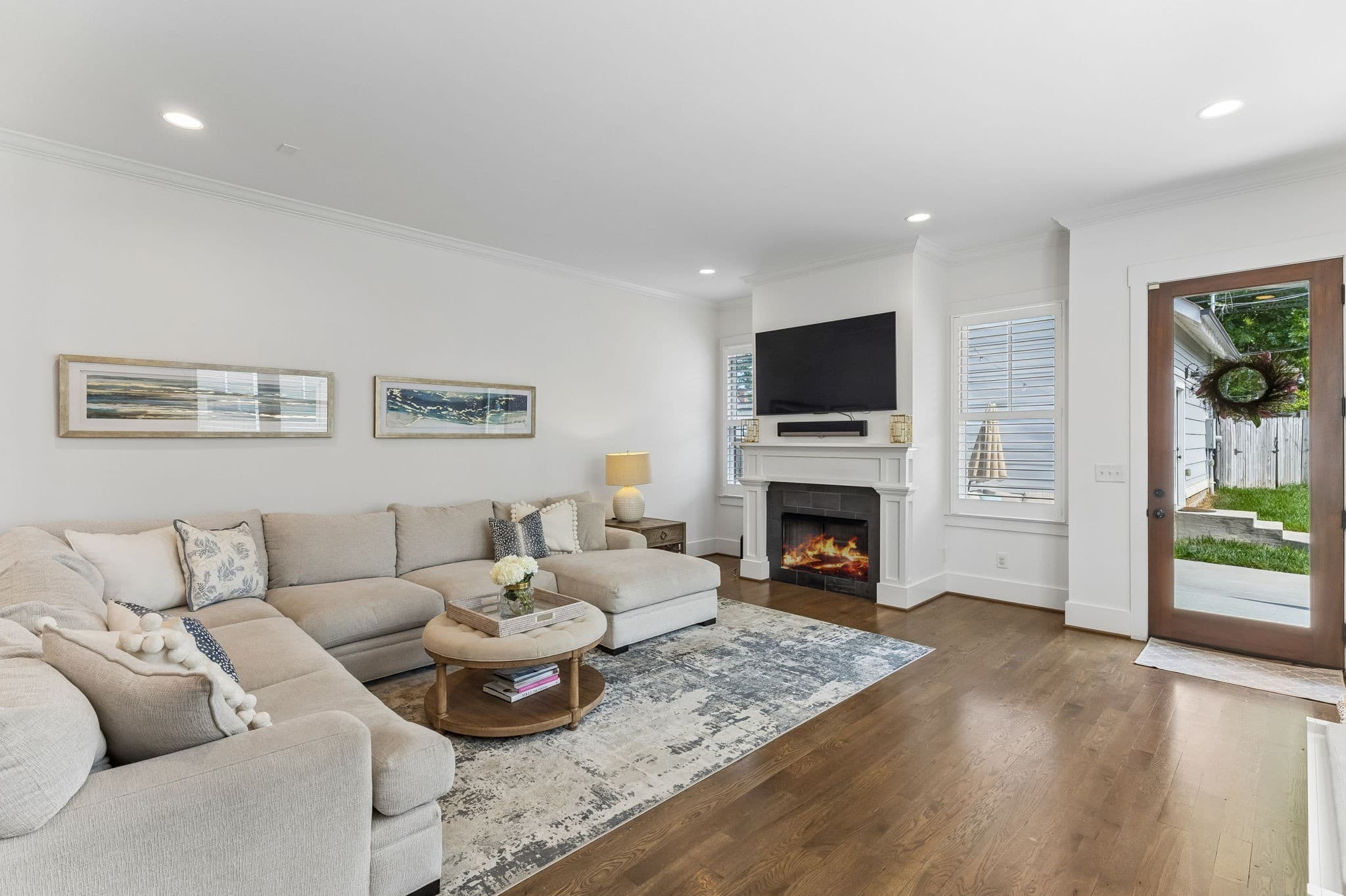 Living room with a gas fireplace, a sectional sofa, hardwood floors and a glass door to the yard at 916 Montrose Avenue #A in 12 South Nashville