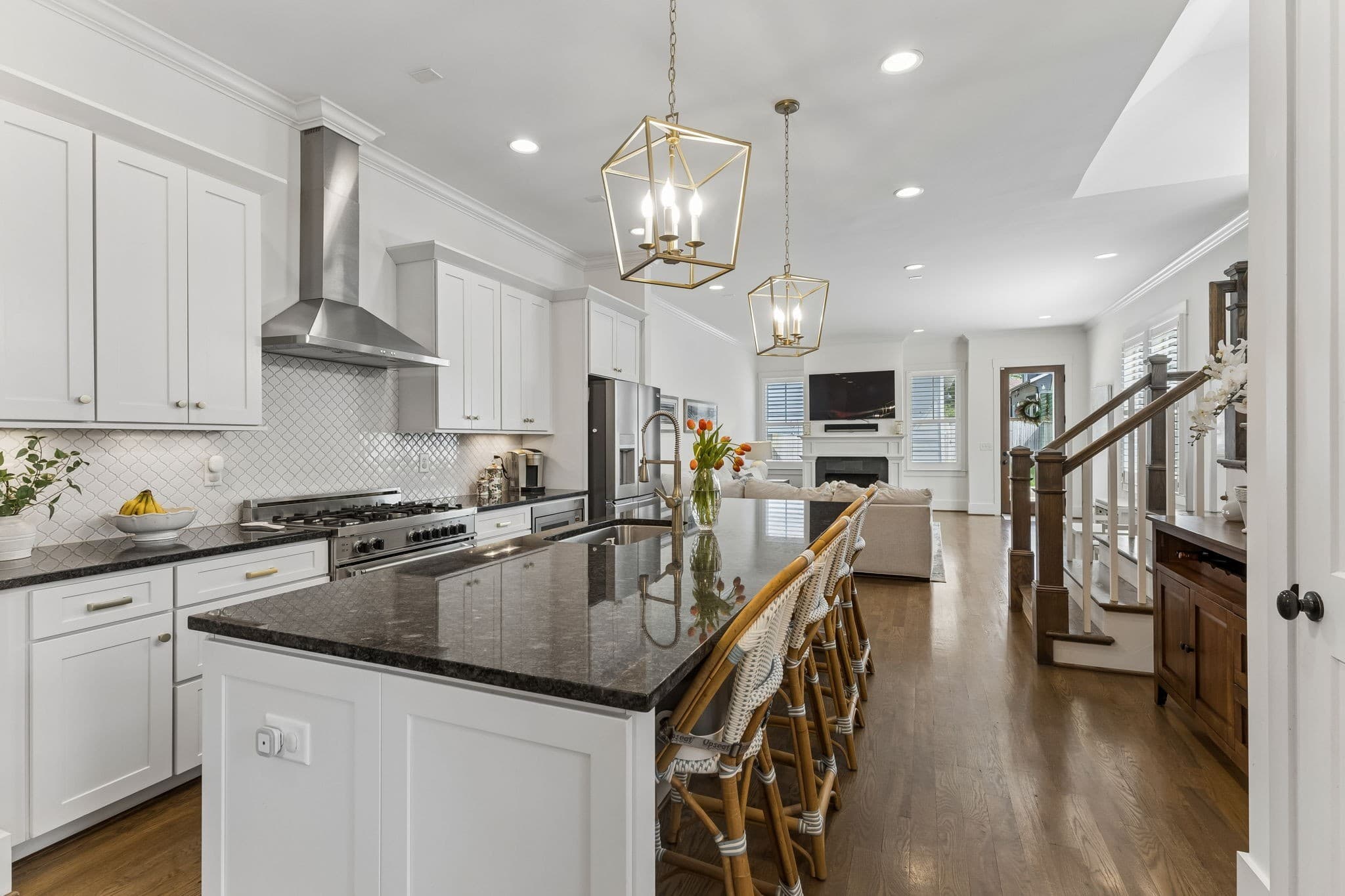 Kitchen with white cabinets, a gas range under a stainless hood, a dark island with seating and lantern pendants at 916 Montrose Avenue #A in 12 South Nashville