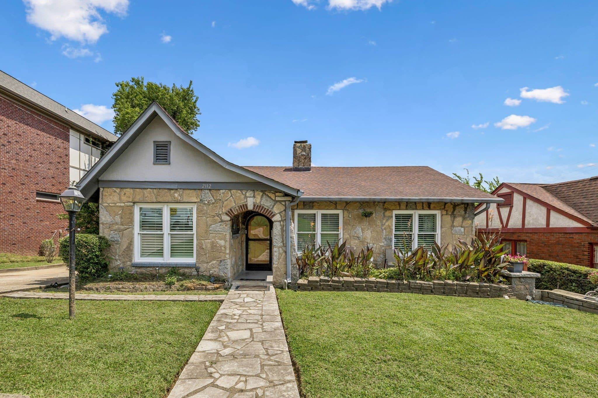 Front exterior of the stone bungalow with an arched entry at 2112 Eastwood Avenue, one of the 12 South homes for sale in 12 South Nashville