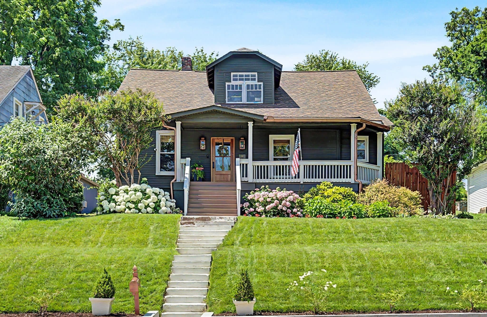 Front exterior of the restored dark-sided home with a covered porch and front dormer at 837 Glen Avenue, one of the 12 South homes for sale in 12 South Nashville