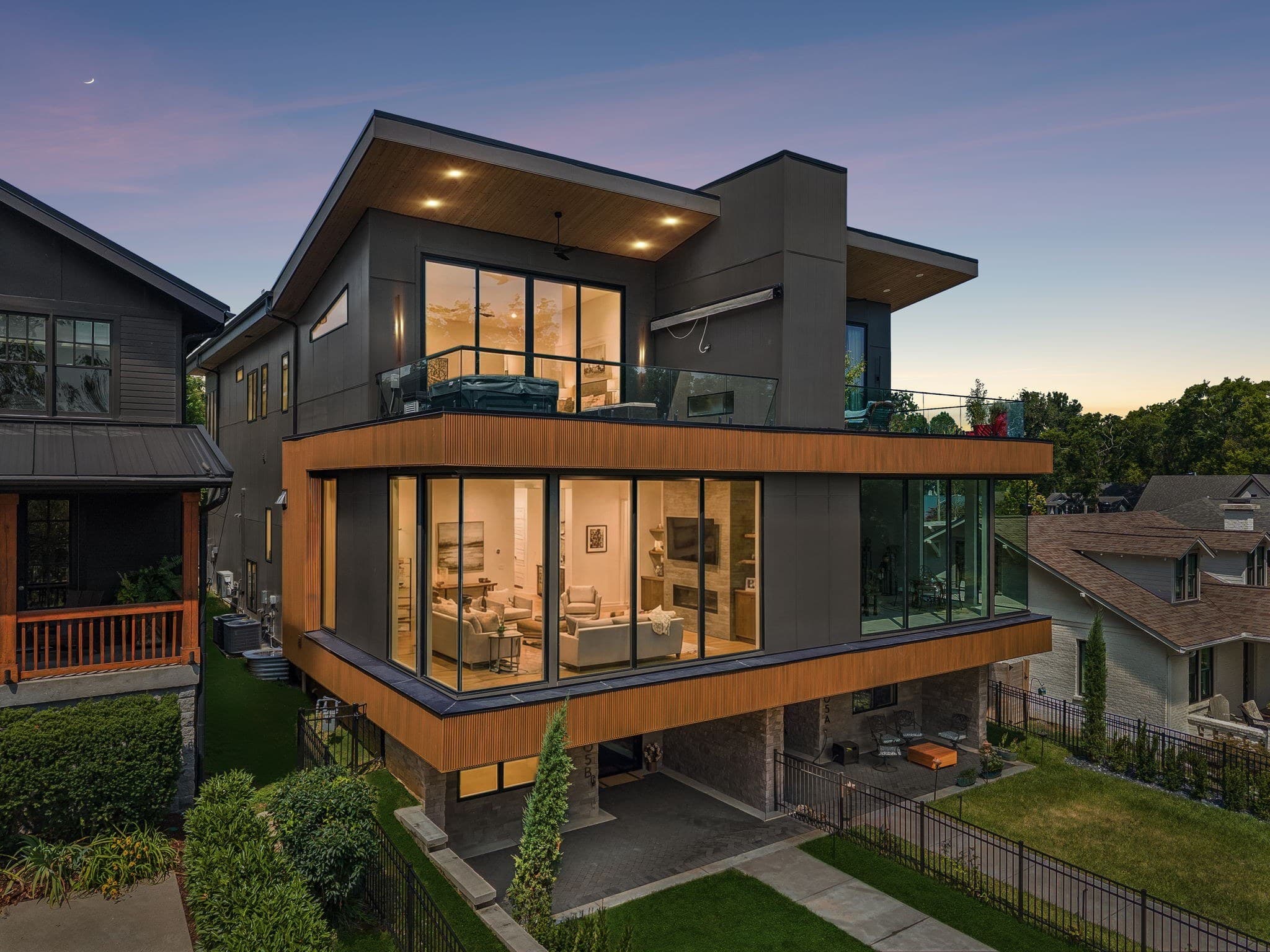 Front exterior of the modern three story home at dusk with glass walls and wood slat accents at 3205B Granny White Pike, one of the 12 South homes for sale in 12 South Nashville