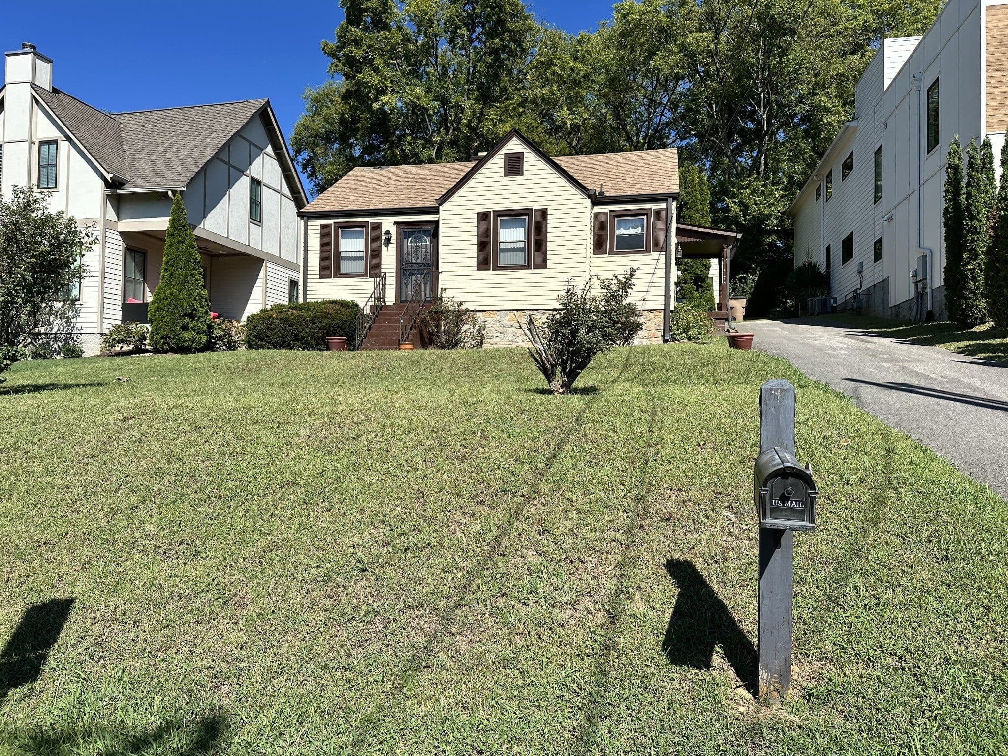 Front exterior of the cream cottage with brown shutters at 820 Horner Avenue, one of the 12 South homes for sale in 12 South Nashville