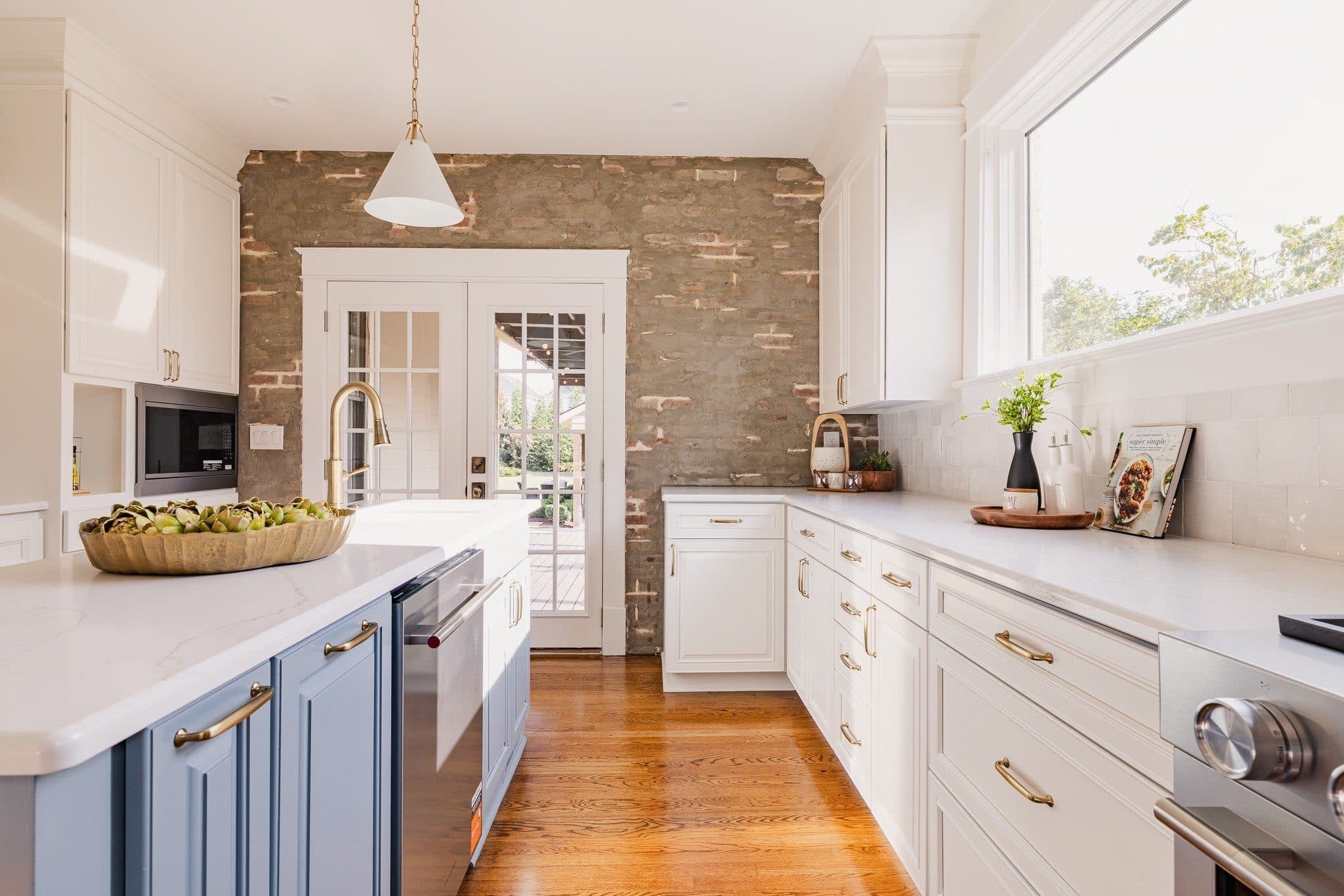 Kitchen with a blue island, white cabinets, and a limewashed brick wall at 941 Inverness Avenue, 12 South Nashville