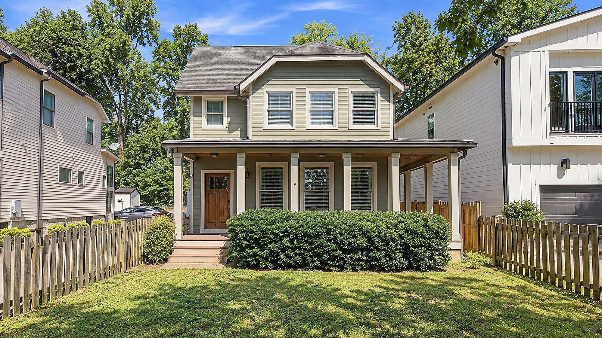 Front exterior of the sage-sided home with a covered front porch and picket fence at 2950 Vaulx Lane, one of the 12 South homes for sale in 12 South Nashville