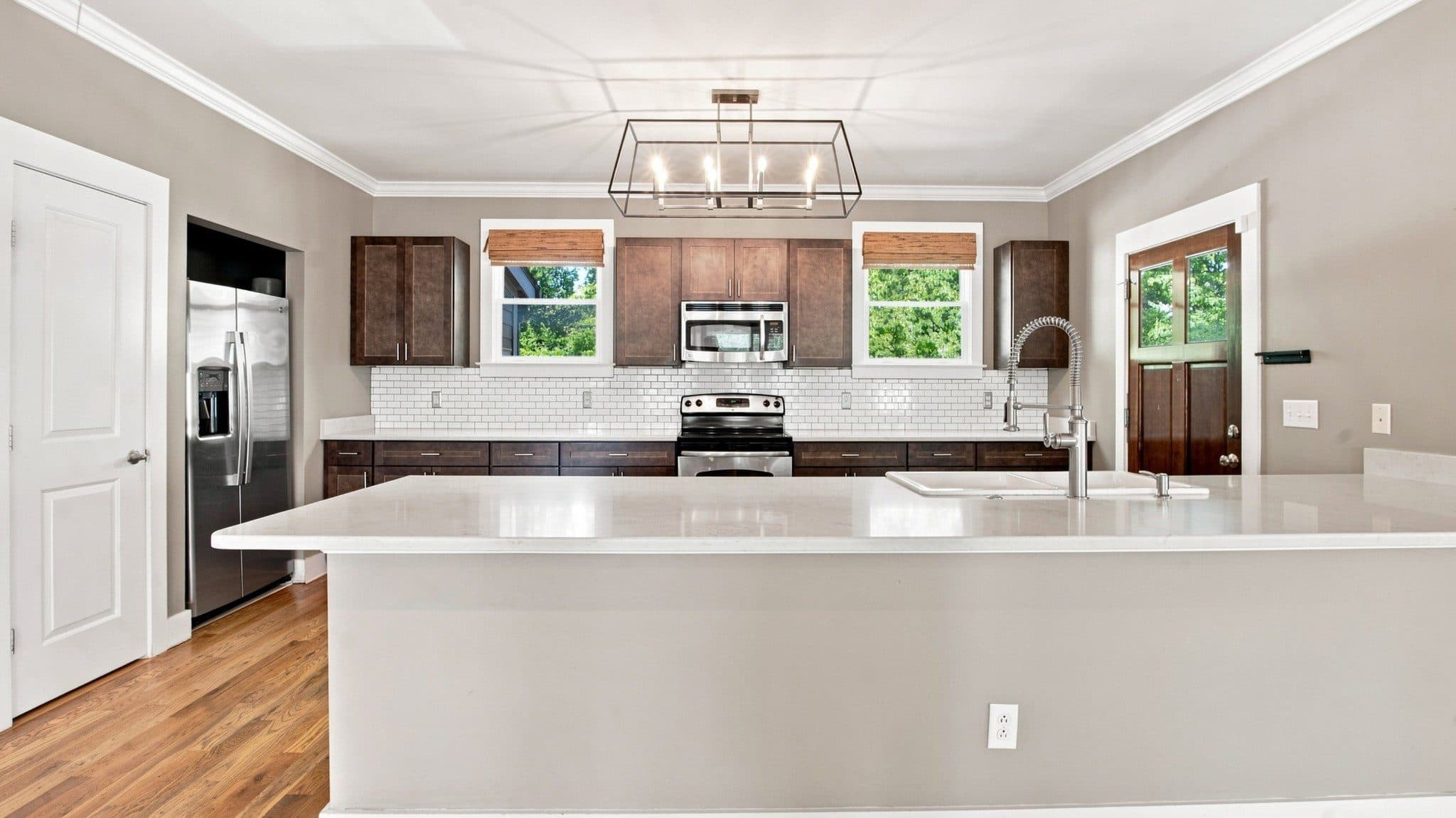 Kitchen with a large white island, dark cabinets, and hardwood floors at 2950 Vaulx Lane, 12 South Nashville