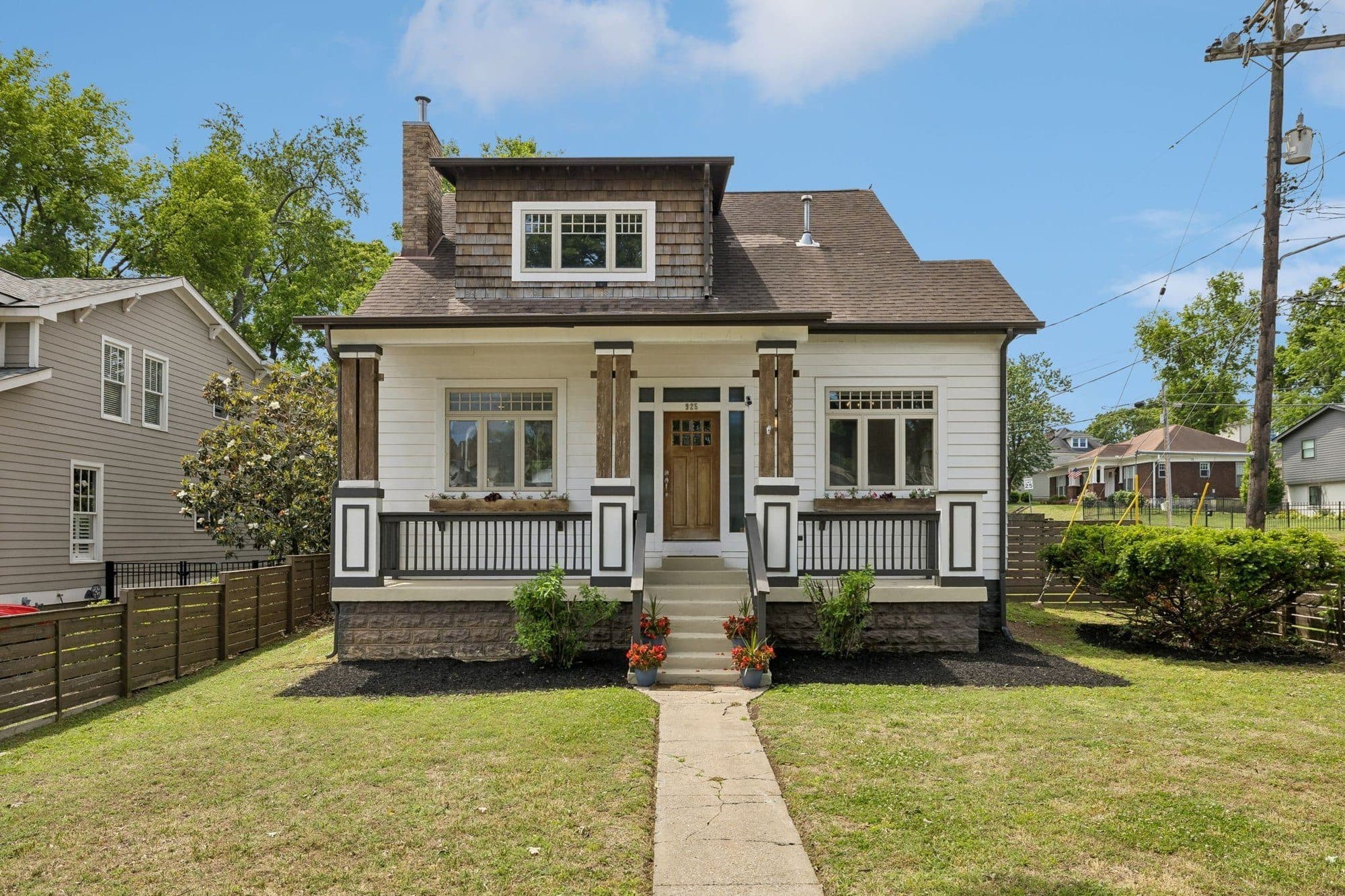 Front exterior of the white Craftsman with a covered porch and wood-shingle dormer at 925 Wedgewood Avenue, one of the 12 South homes for sale in 12 South Nashville